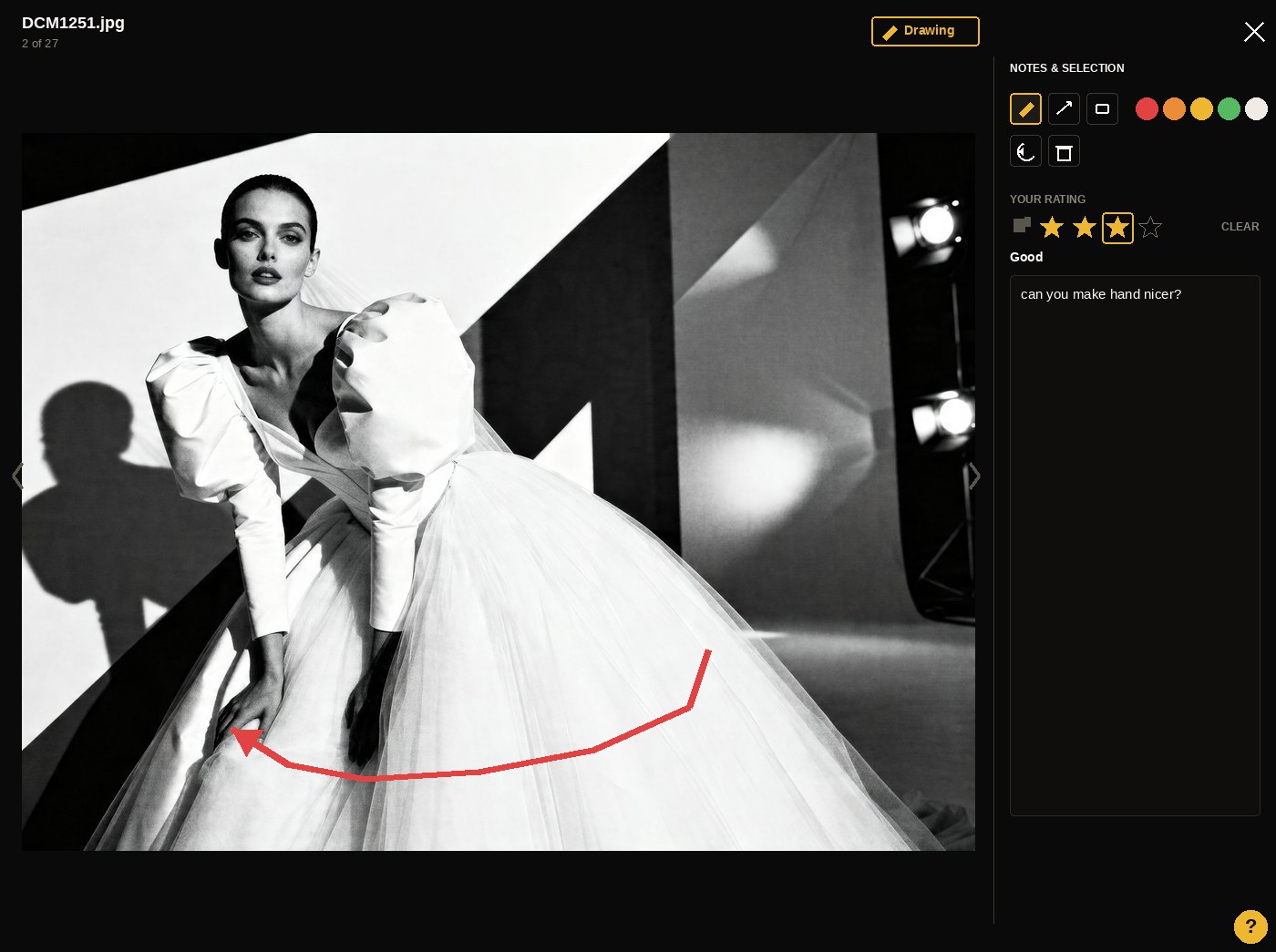 A photographer reviewing a grid of black-and-white portrait proofs on a monitor, with warm window light and ambient lamp glow.